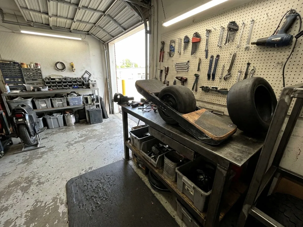 One-wheeled electric skateboard on a workbench with its tire off and the hub motor exposed