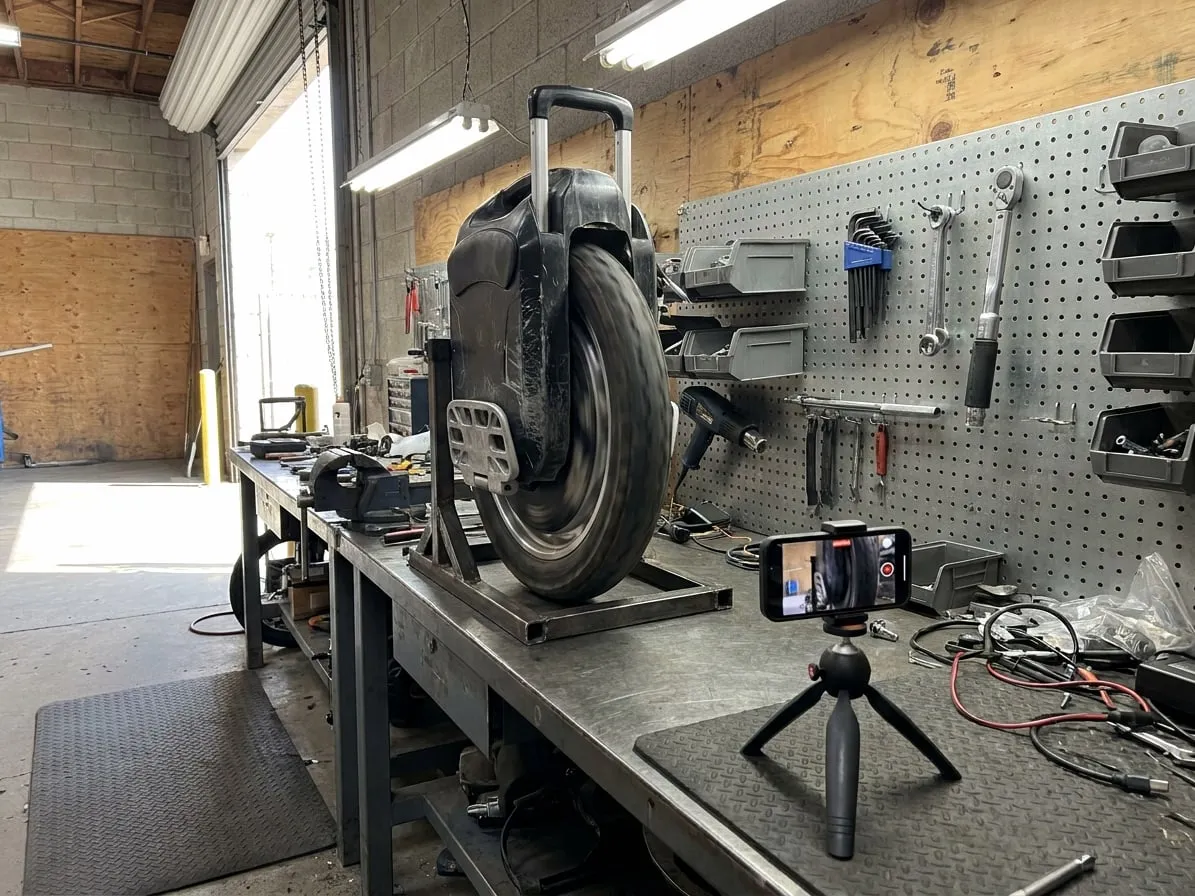 Phone on a tripod recording an electric unicycle wheel spinning on a repair stand during its final test